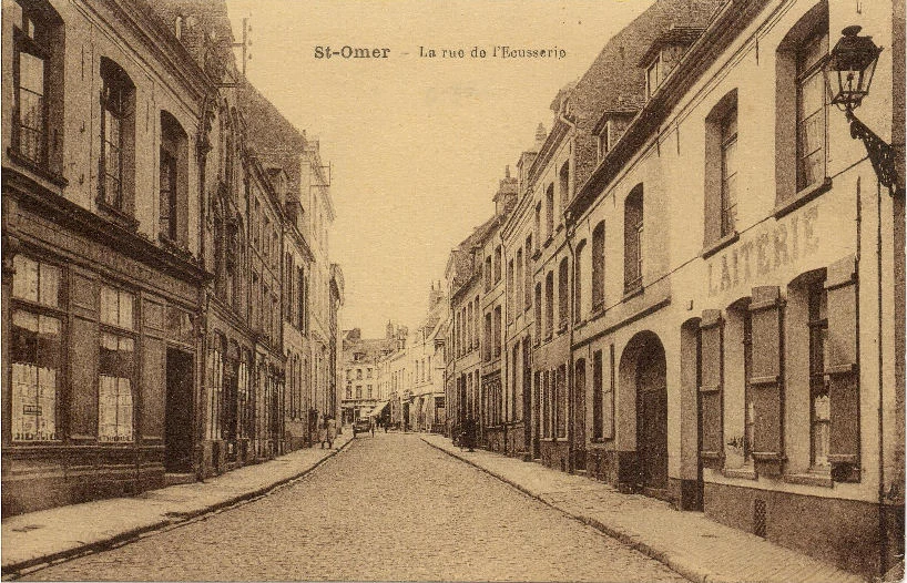 (b)- en remontant la rue