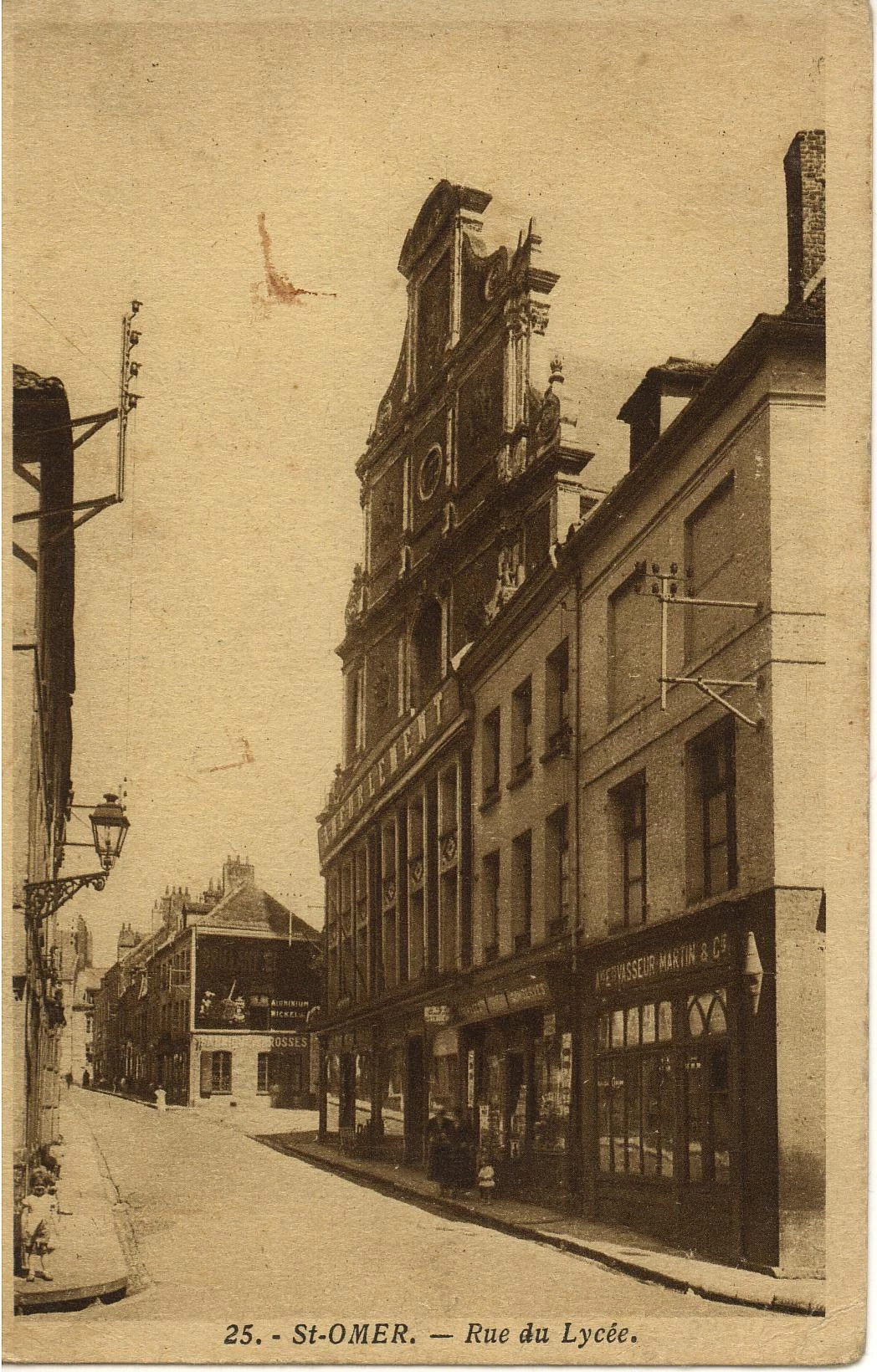 (b)-En bas de la rue